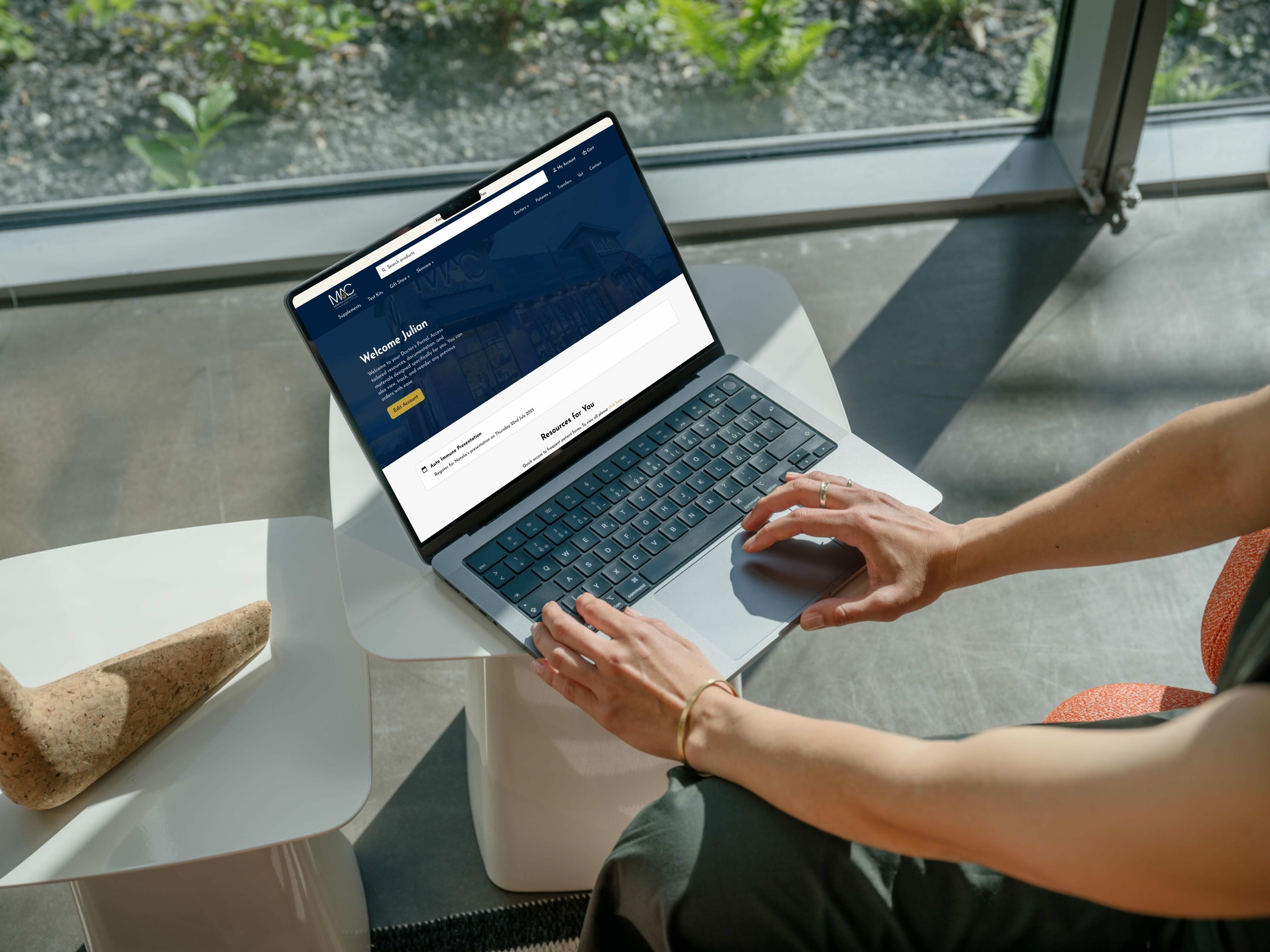 Person using a laptop on a small table with a window view
